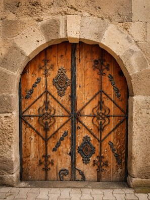 Una puerta de madera con detalles de metal labrado, ubicada en un arco de piedra.
