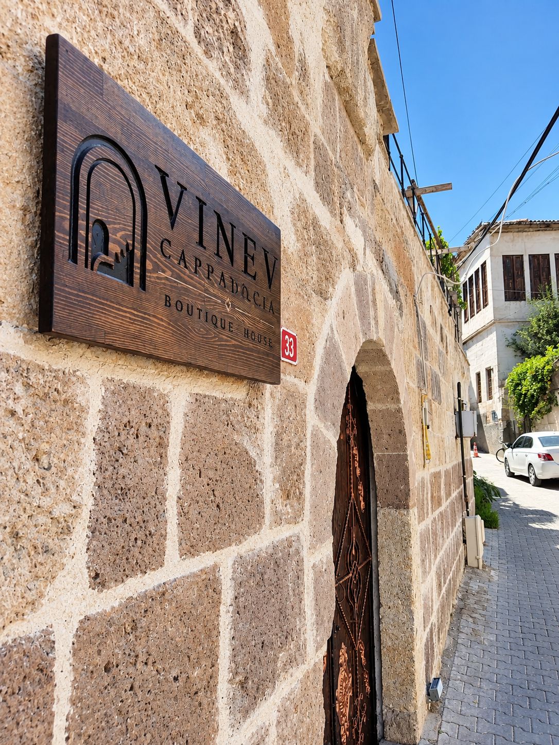 Un letrero que dice 'VINEV CAPPADOCIA Boutique House' en una pared de piedra.