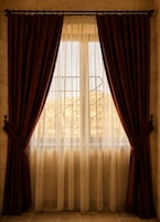A window with a sheer curtain and a solid drape, a metal rod, and a view of a tree outside.