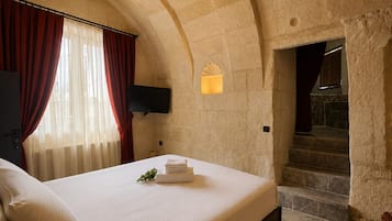Un dormitorio con una cama grande, cortinas rojas, un televisor de pantalla plana y una escalera que lleva a un nivel superior.