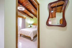 Een slaapkamer met een bed, nachtkastje, lamp en plafondventilator.