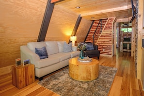 Una sala de estar acogedora con un sofá, una mesa de centro y una escalera que conduce a un nivel superior.