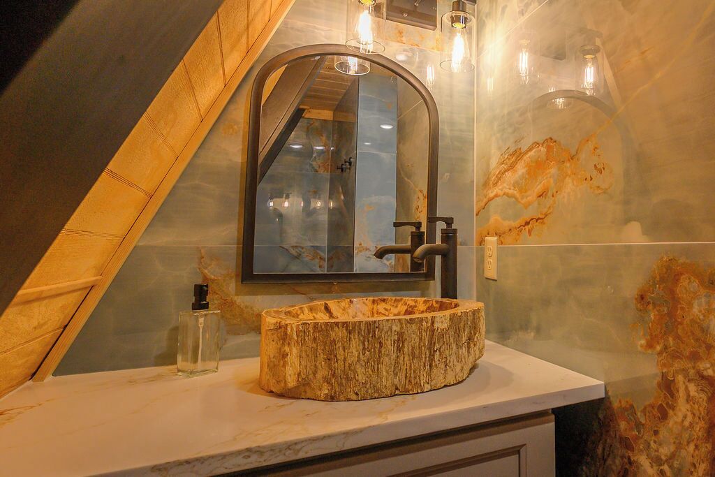 A bathroom with a wooden vanity, a mirror, and a modern faucet.
