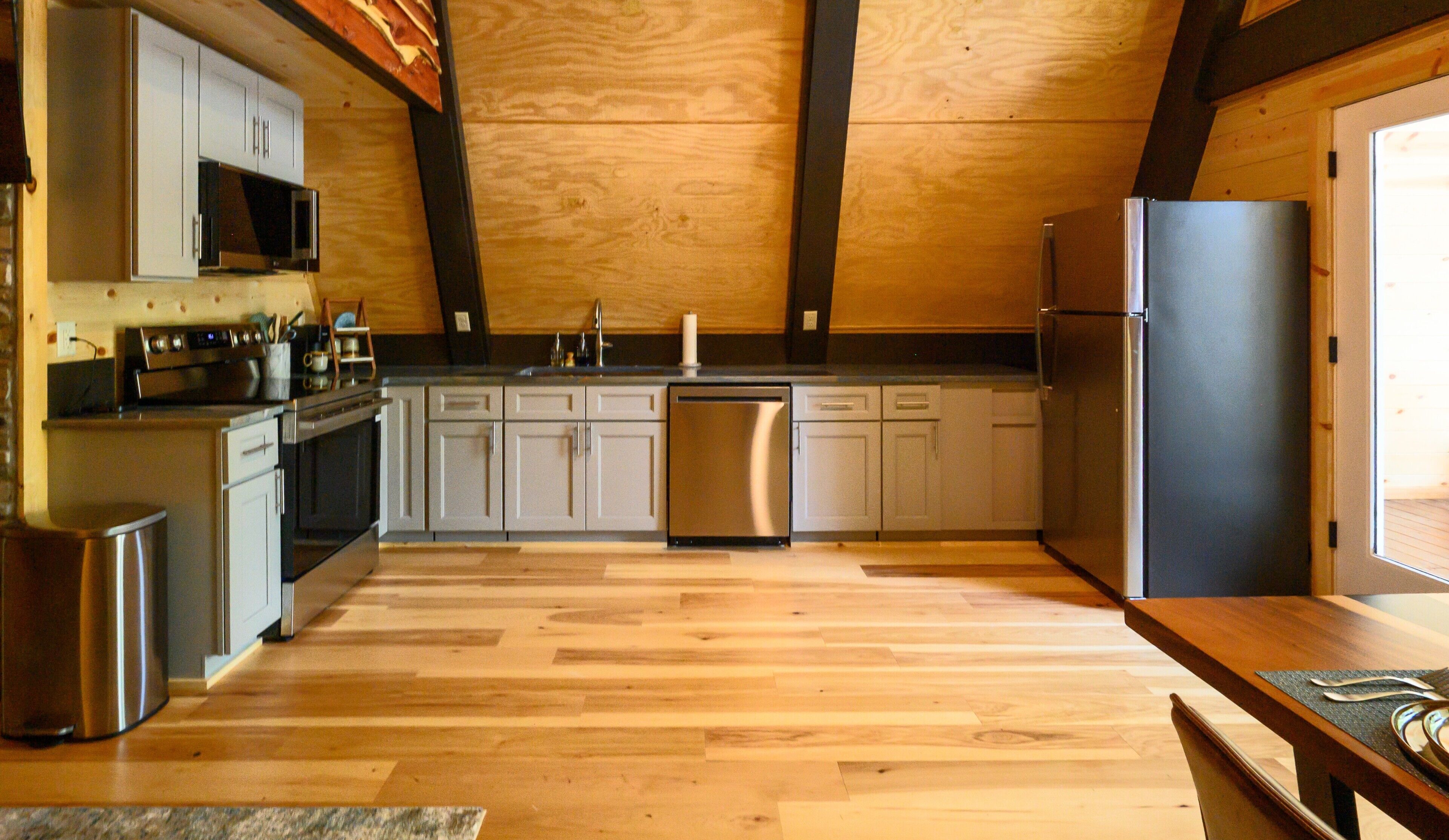Une cuisine moderne avec un plancher en bois, des appareils électroménagers en acier inoxydable et un îlot central.