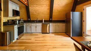 Une cuisine moderne avec un plancher en bois, des appareils électroménagers en acier inoxydable et un îlot central.