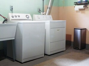 A laundry area with two washing machines and a dryer.