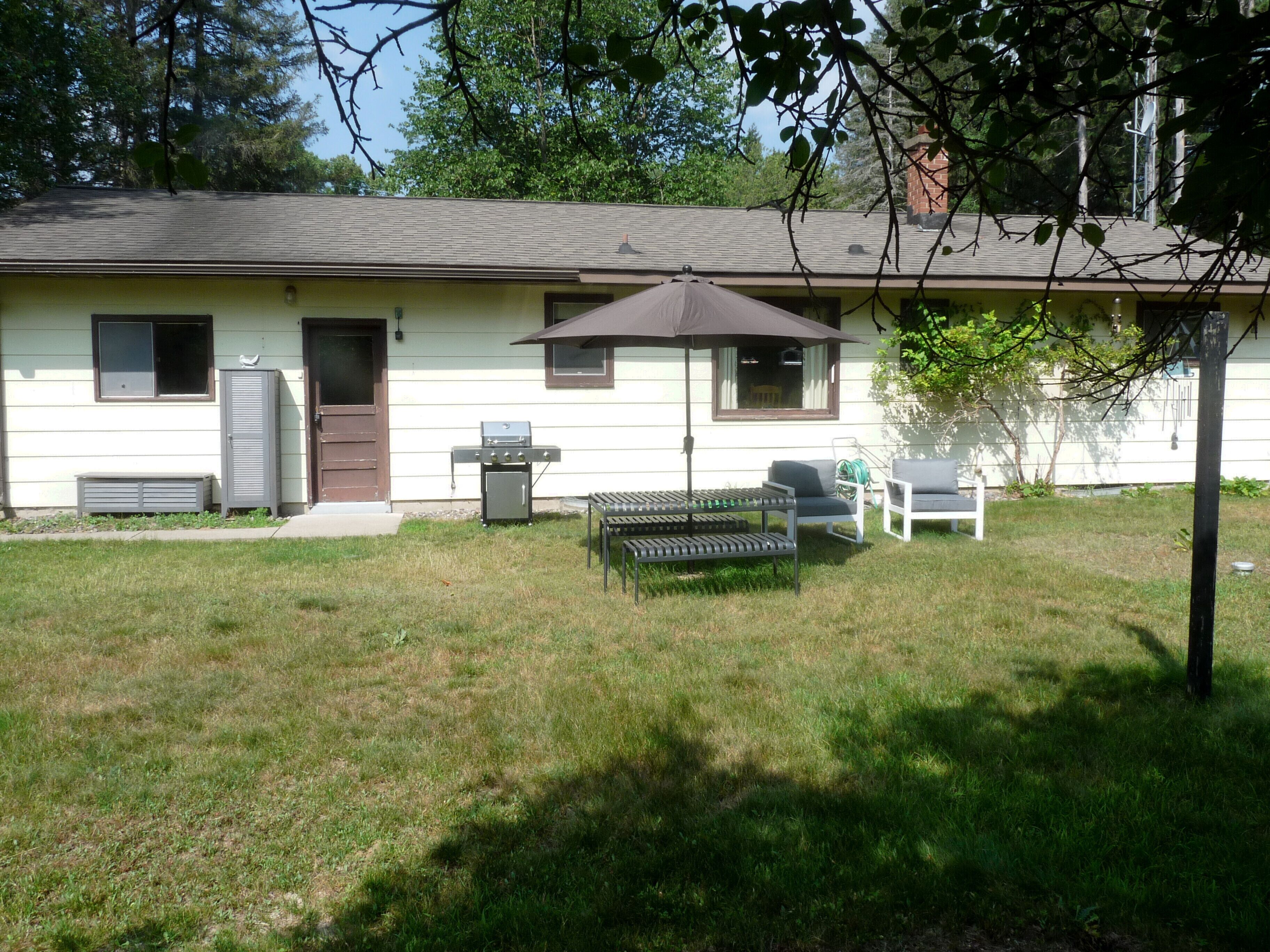 A single-story building with a patio area, a grill, and outdoor seating.