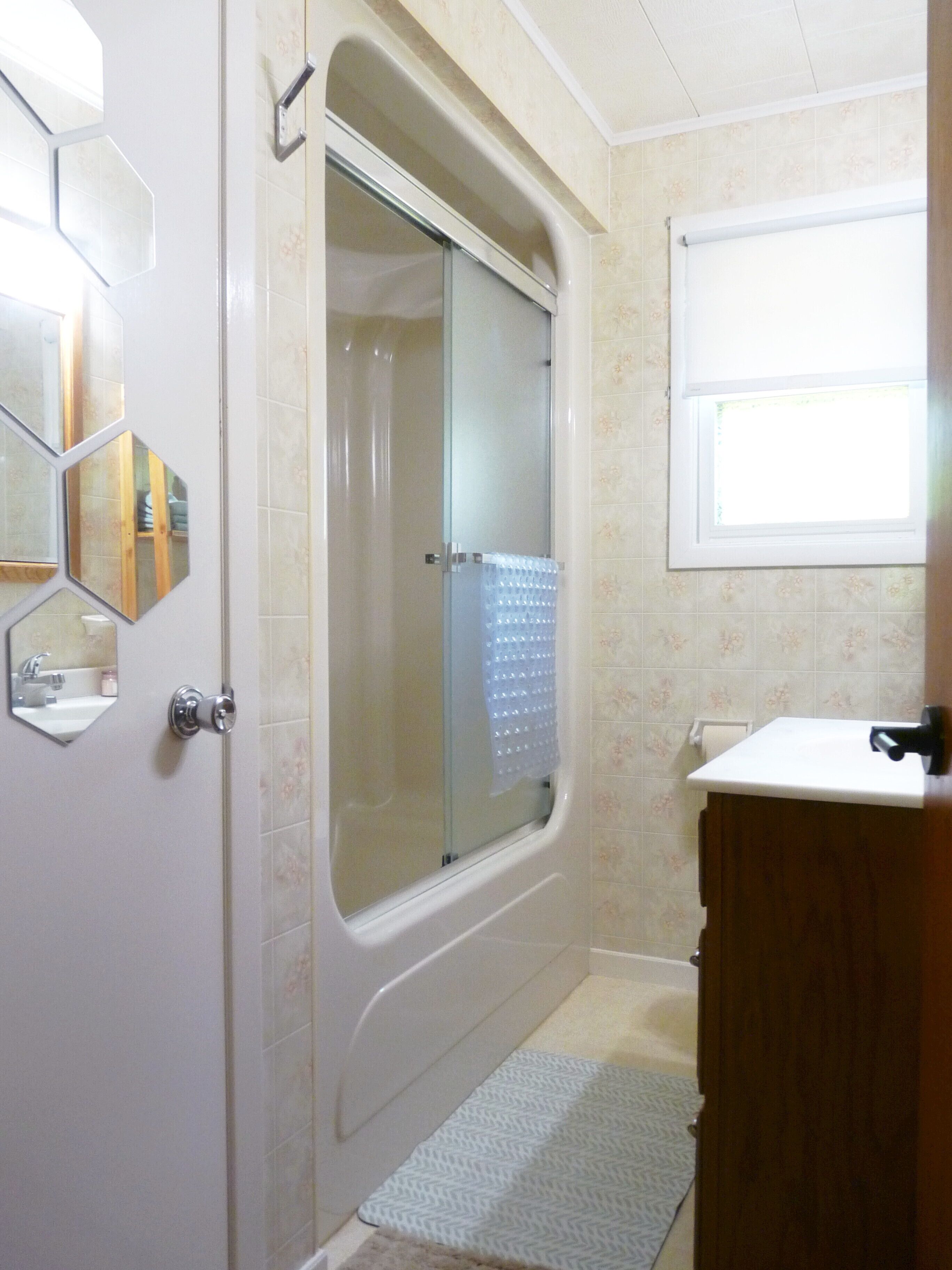 A bathroom with a shower, a sink, and a mirror.