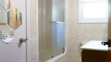 A bathroom with a shower, a sink, and a mirror.