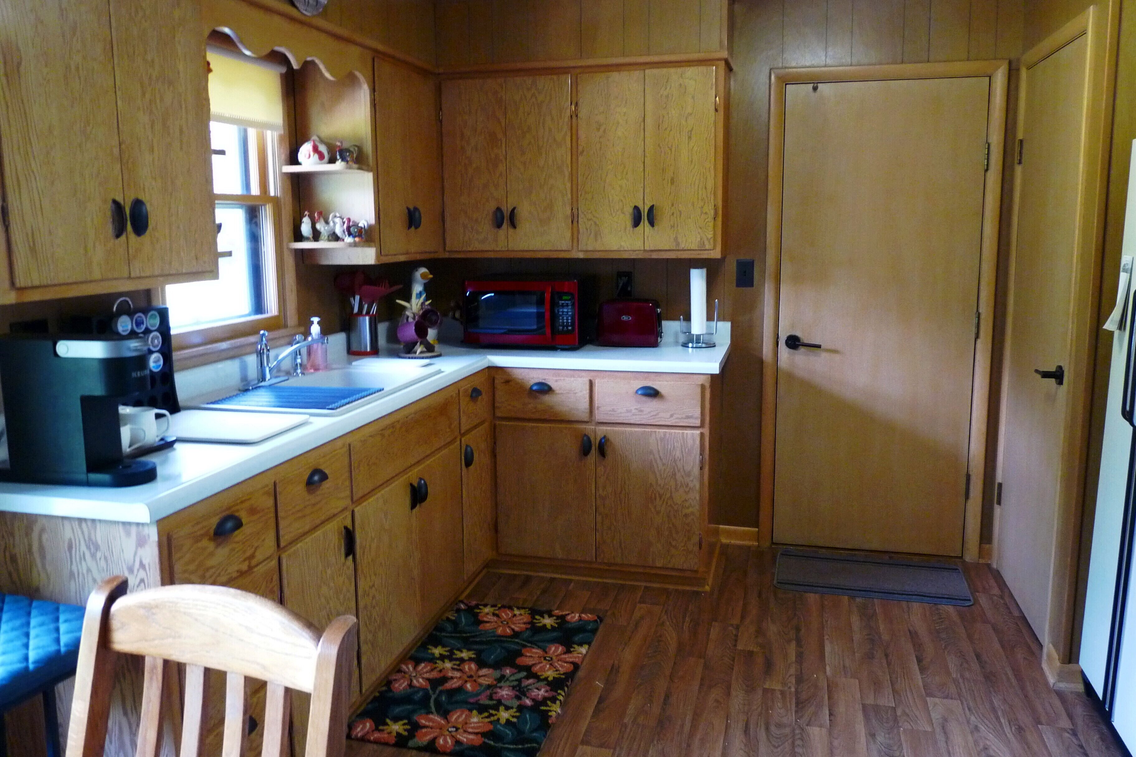 Una cocina compacta con armarios de madera, un microondas, un tostador y una cafetera.