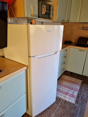 A compact kitchen with a white refrigerator, a microwave, and a small countertop.