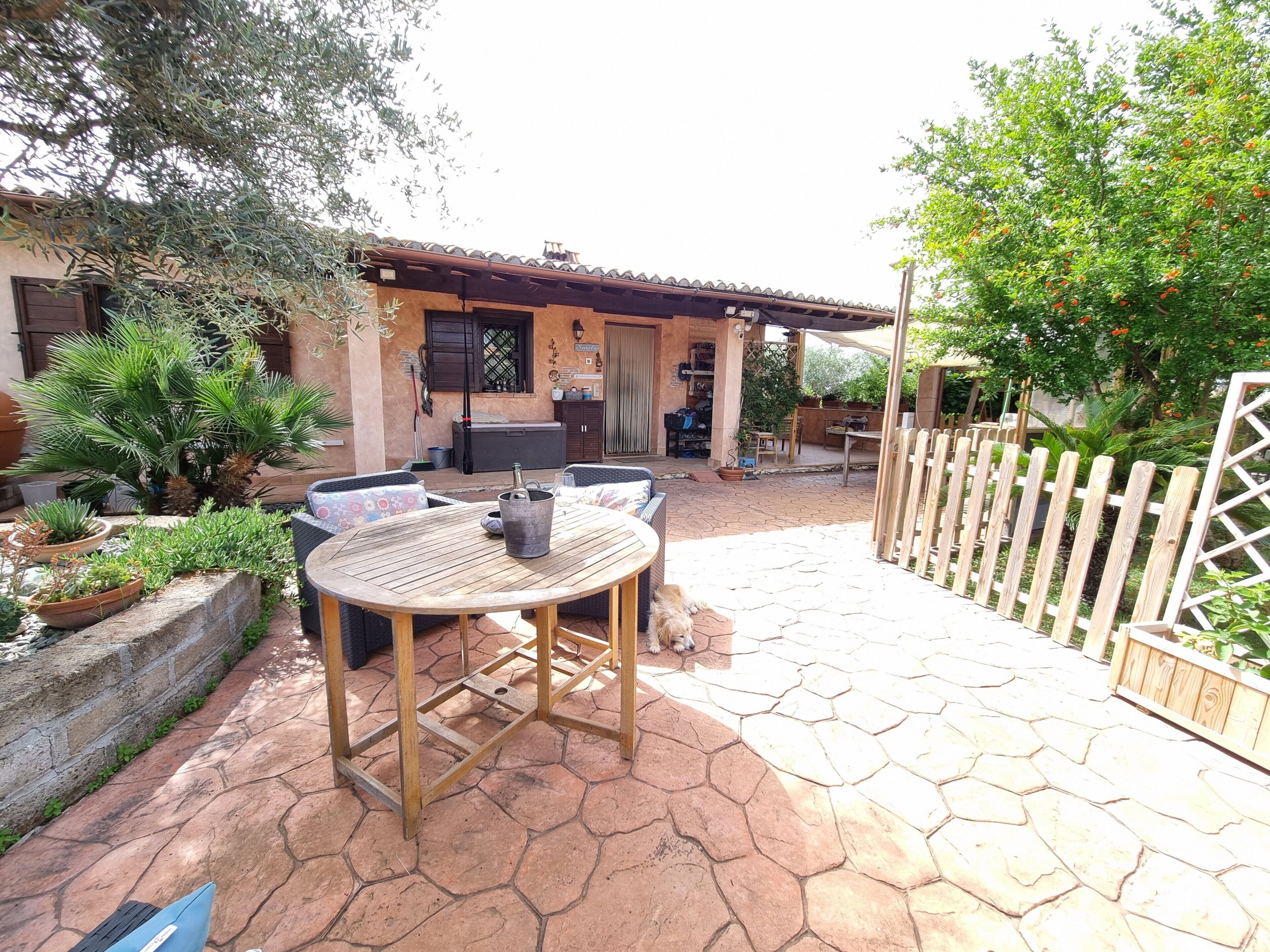 A patio with a round table and chairs, a barbecue area, and a wooden fence.