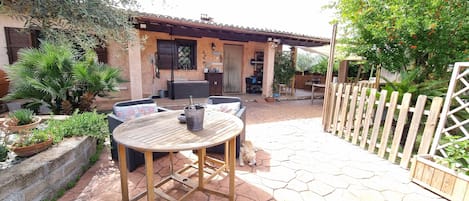 A patio with a round table and chairs, a barbecue area, and a wooden fence.