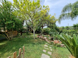 A garden with a variety of plants, a wooden fence, and a stone pathway. - Villa Shiva - Extension. Country House with Hot Tub and Grill (Lazio)