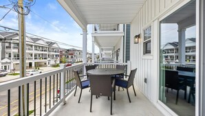 Een balkon met een tafel en stoelen, uitkijkend op een straat met hoge gebouwen.