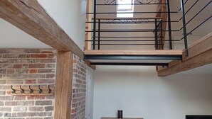A loft-style room with exposed brick walls, a wooden ceiling, and a black metal staircase.