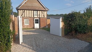 Een huis met twee verdiepingen en een grindpad dat naar een witte garagepoort leidt.