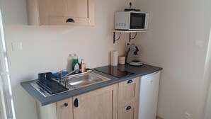 A compact kitchen with a built-in microwave, a sink, and a coffee machine.