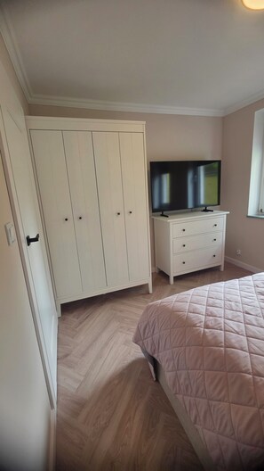 Une chambre à coucher avec un lit, un téléviseur posé sur une commode et une armoire.