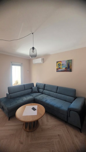 A living room with a sectional sofa, a wooden coffee table, and a painting on the wall. - 50-square-meter vacation rental in Międzyzdroje, 500 meters from the beach, 3 rooms. (Międzyzdroje)