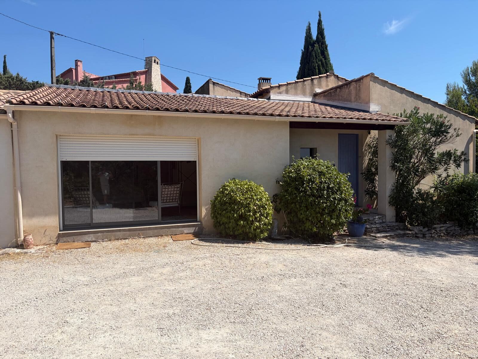 A residential building with a tiled roof, a garage door, and a gravel driveway.