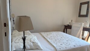 Un letto singolo con copripiumino bianco e comodino con lampada.