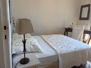 Una cama individual con una colcha blanca y una mesita de noche con lámpara.