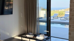 Ein Zimmer mit großem Fenster, das einen Blick auf einen Pool und das Meer bietet.