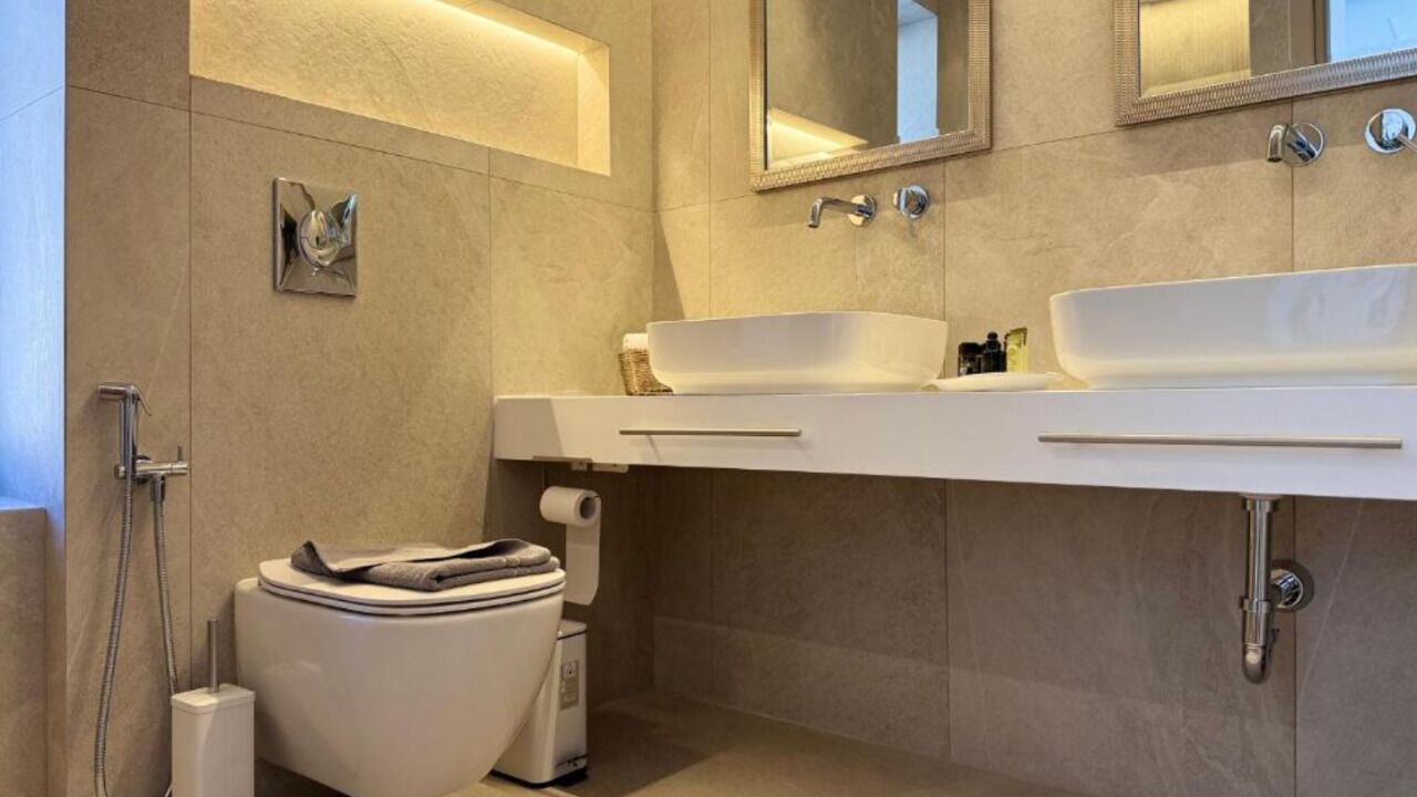 A modern bathroom with a white sink, a mirror, and a toilet.