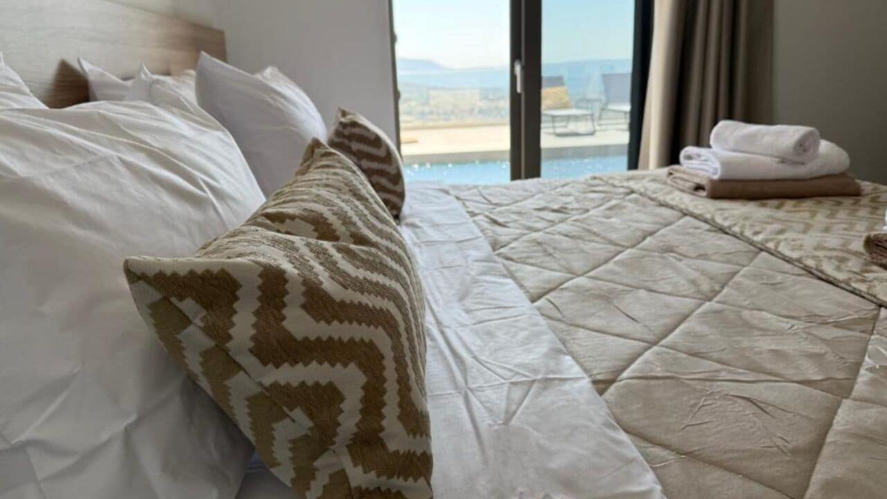 A hotel room with a bed, a view of the sea, and a window with curtains.
