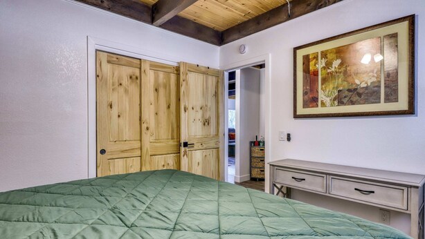 Una camera da letto con un letto verde trapuntato, un'armadiatura in legno e un'opera d'arte appesa al muro.