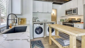 Una cucina compatta con lavatrice, forno a microonde e lavello.