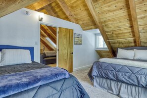 A bedroom with two beds, a wooden ceiling, and a door leading to another room. - Classic Tahoe Cabin Near Beaches, Mountain Bike Trails & Year-Round Adventure (South Lake Tahoe)