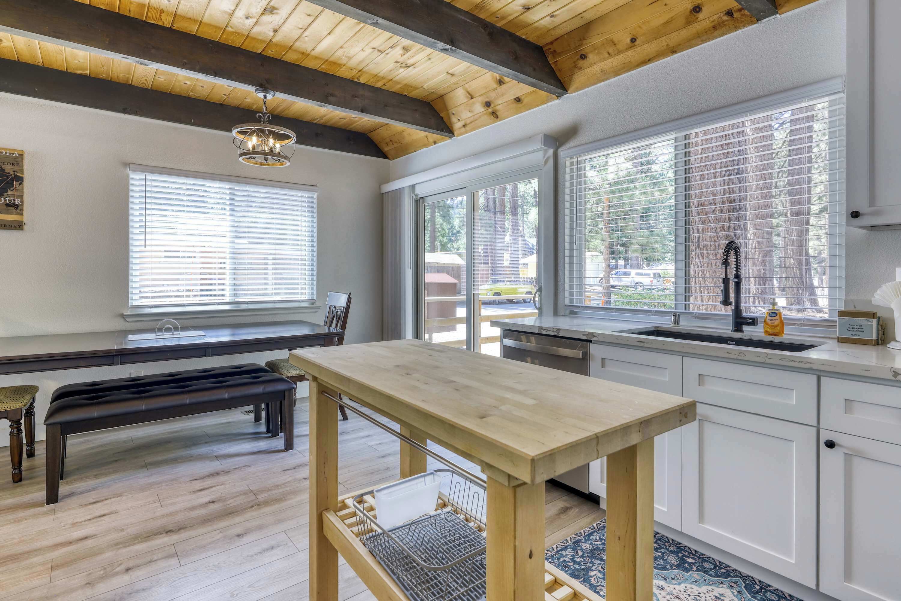 A kitchen with a wooden table, a bench, and a window with blinds.