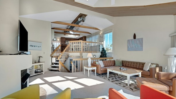 Ein geräumiger Wohnbereich mit einer Treppe zu einer oberen Etage, einem Flachbildfernseher und einem Weihnachtsbaum.