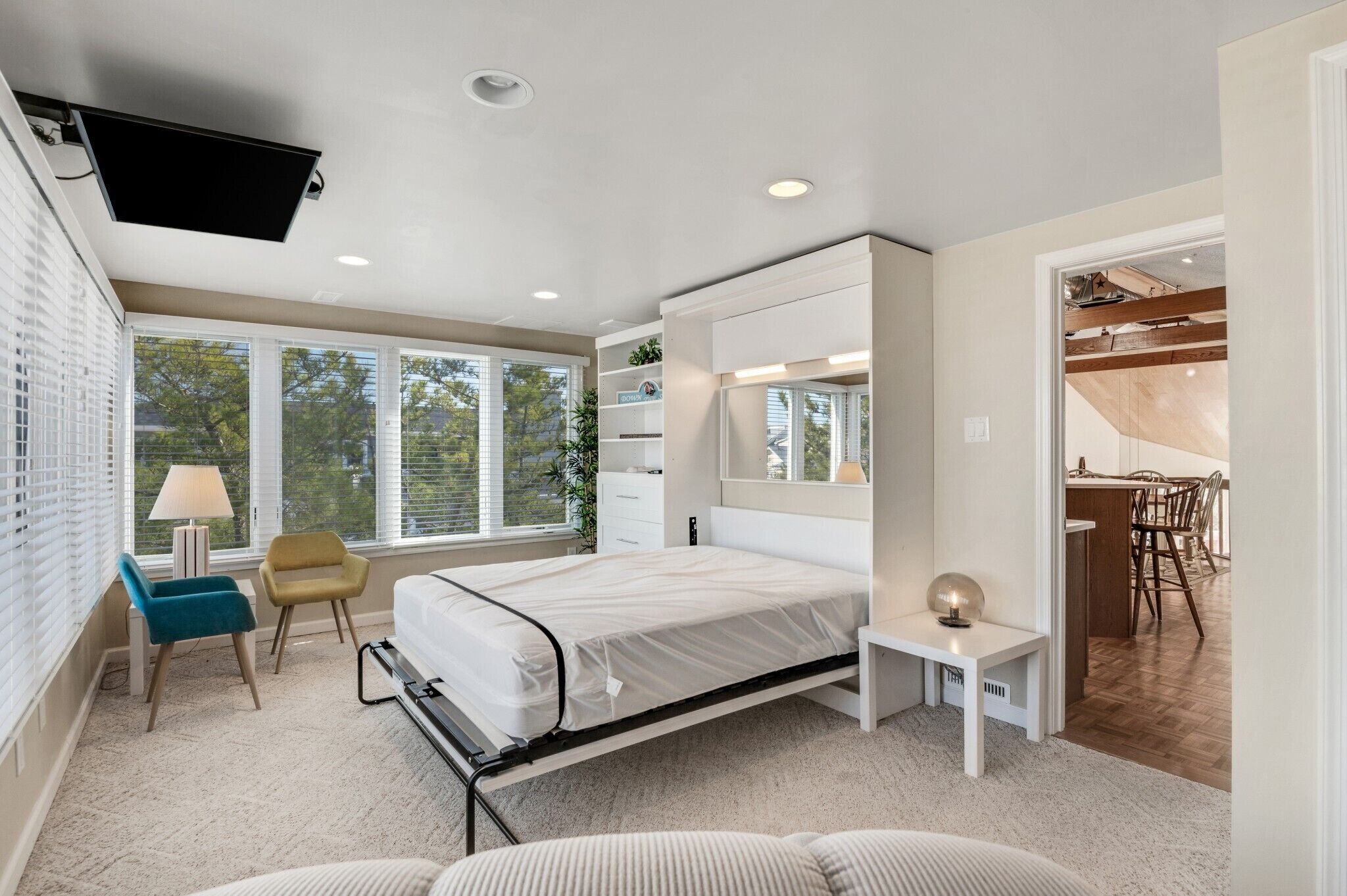 A modern bedroom with a bed, bedside table, chair, and a desk area with a chair.