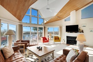 A spacious living room with a fireplace, comfortable seating, and large windows offering a view of the outdoors. - Marvelous 5-bedroom beachfront townhome in Ocean City (Ocean City)