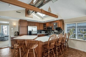A modern kitchen with a central island, wooden chairs, and a view of the outside. - Marvelous 5-bedroom beachfront townhome in Ocean City (Ocean City)