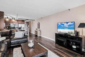 A modern living room with a leather sofa, wooden coffee table, and a flat-screen TV. - Pelican Cove 505 - A Quiet Getaway Awaits (Indian Rocks Beach)