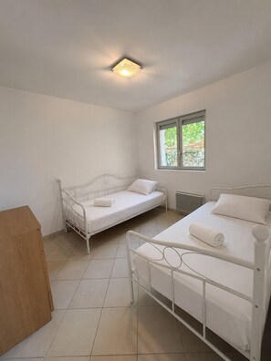 Ein Schlafzimmer mit zwei Betten, einem Fenster und einer Heizung.