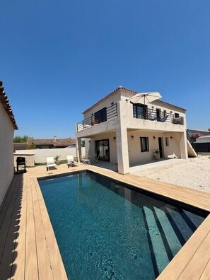 Ein zweistöckiges Haus mit Pool im Hinterhof.