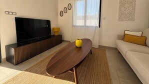 A modern living room with a flat-screen TV, a wooden coffee table, a sofa, and a patterned rug. - Olia - Private pool close to the city center (L'Isle-sur-la-Sorgue)