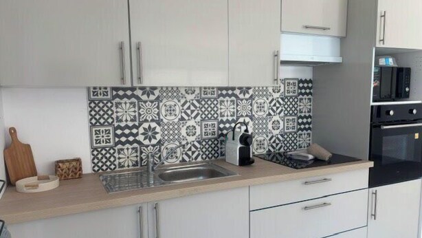 A modern kitchen with white cabinets, a patterned backsplash, and a built-in oven. - Olia - Private pool close to the city center (L'Isle-sur-la-Sorgue)