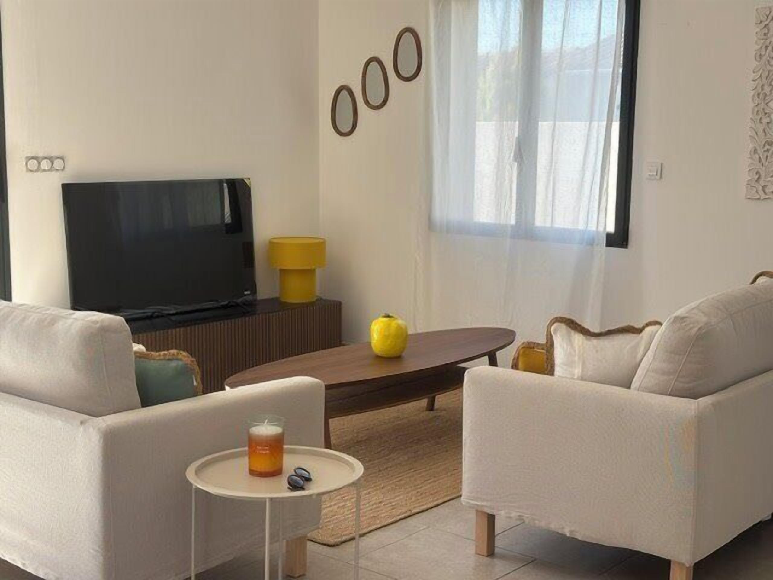 Un salon avec un canapé, une table basse, un téléviseur et une petite table sur laquelle se trouve une boisson.