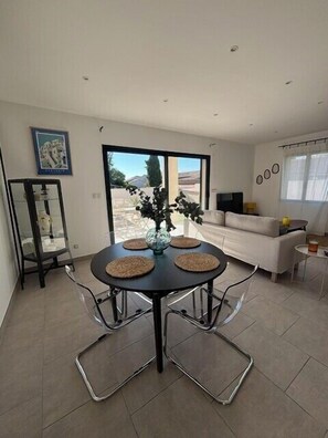A modern dining area with a round table, four chairs, and a vase of flowers. - Olia - Private pool close to the city center (L'Isle-sur-la-Sorgue)