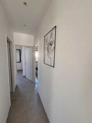 Ein Flur mit Fliesenboden, weißen Wänden und einem gerahmten Kunstwerk.