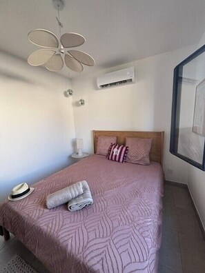 Ein Schlafzimmer mit Bett, Deckenventilator, Klimaanlage und Fenster.
