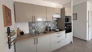 Uma cozinha moderna com armários brancos, painel de backsplash preto e branco e bancada de madeira.