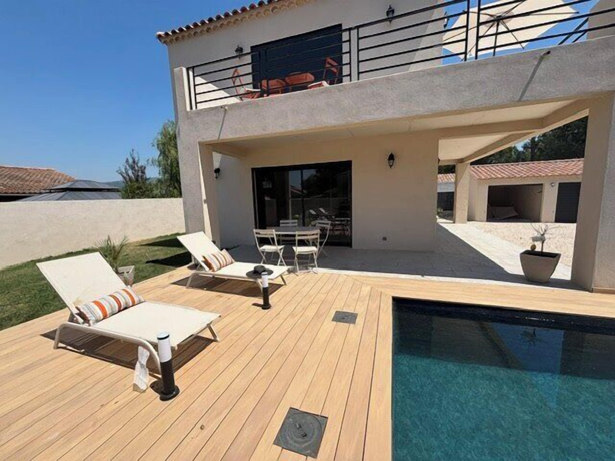 A two-story house with a swimming pool, outdoor furniture, and a covered patio area.