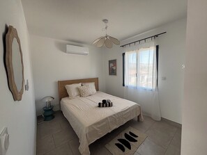 Ein Schlafzimmer mit einem Bett, einem Deckenventilator, einer Klimaanlage, einem Fenster mit Vorhängen und einem Teppich.